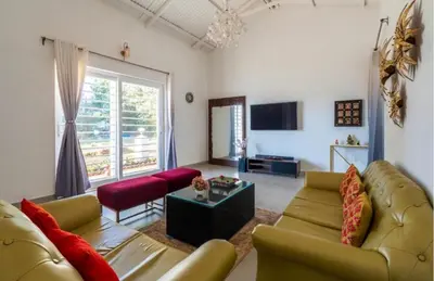 a living room with two couches and a tv at The Lake House Ooty in Ooty