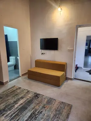 a living room with a couch and a flat screen tv at The Lake House Ooty in Ooty