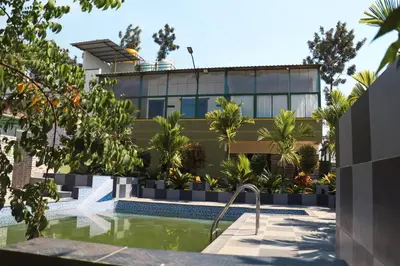a house with a swimming pool in front of a building at Nature's Spark Resort in Sivasamudram