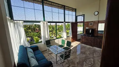 a living room with a blue couch and large windows at Nature's Spark Resort in Sivasamudram