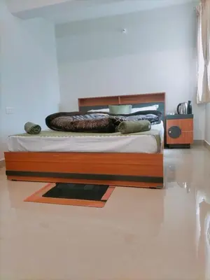 a bed with a wooden frame in a room at Noori Home Stay - 2BH in 1st Floor Near Ooty in Ooty