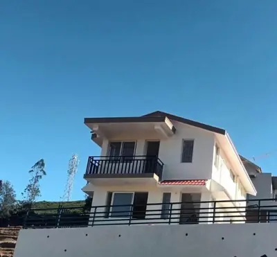 a white house with a balcony on top of a wall at Noori Home Stay - 2BH in 1st Floor Near Ooty in Ooty