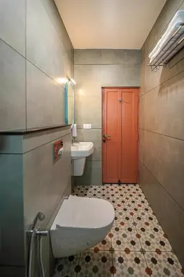 a bathroom with a toilet and a sink and a red door at Sreenivas Lodge by Copperfolia in Kozhikode