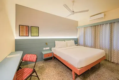 a bedroom with a bed and a chair in it at Sreenivas Lodge by Copperfolia in Kozhikode