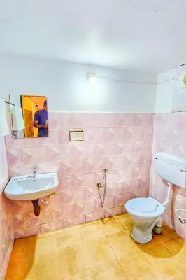 a pink bathroom with a sink and a toilet at TS Club in Trichūr