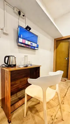 a white chair and a television on a wall at TS Club in Trichūr