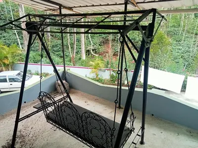 a swinging bed in a room with a window at Somanna Estate stay in Madikeri