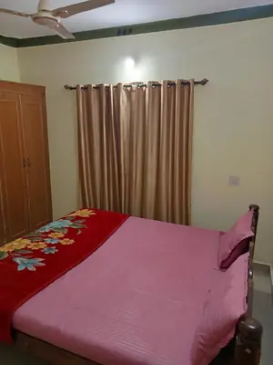 a bedroom with a bed with a red blanket at Somanna Estate stay in Madikeri