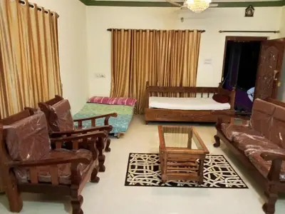 a living room with a couch and chairs and a bed at Somanna Estate stay in Madikeri