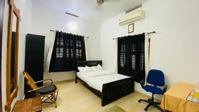 a bedroom with a bed and two chairs and a table at Green Island homestay in Kadalundi