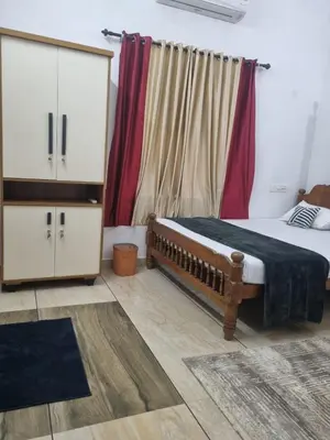 a bedroom with a bed and a dresser and curtains at Green Island homestay in Kadalundi