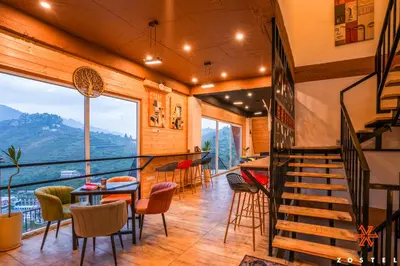 a room with a staircase and a table and chairs at Zostel Kodaikanal, Vilpatti in Kodaikānāl