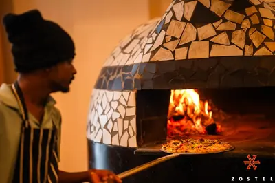 a man is putting a pizza into an oven at Zostel Kodaikanal, Vilpatti in Kodaikānāl