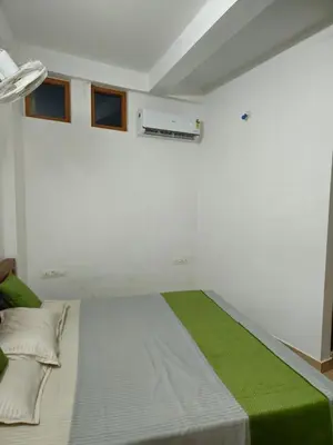 a bedroom with a large bed with a green blanket at RF Tower Lodge in Kozhikode