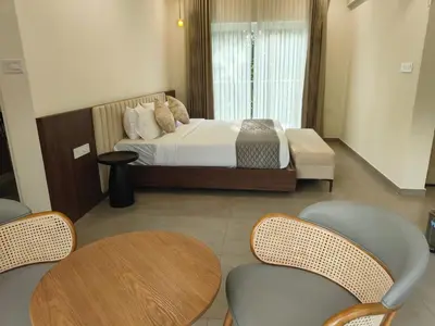 a bedroom with a bed and tables and chairs at Half Moon Resort Vythiri by Z Vacations in Vayittiri