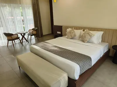 a bedroom with a large bed with a table and chairs at Half Moon Resort Vythiri by Z Vacations in Vayittiri