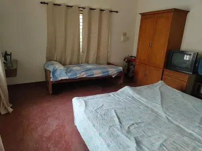 a bedroom with a bed and a tv and a dresser at Deshadan's Kesarvilla in Palakkad
