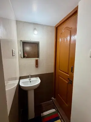 a bathroom with a sink and a toilet and a door at Anand's Elegant 2BHK Apartment - AC in Mysore