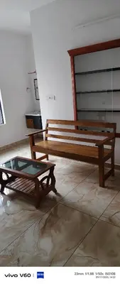 a room with two wooden benches and a glass table at Happy Homes in Palakkad
