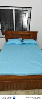 a wooden bed with blue sheets and blue pillows at Happy Homes in Palakkad