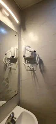 a bathroom with a mirror and a toilet and a sink at Radha Madhavam Apartment's in Guruvāyūr