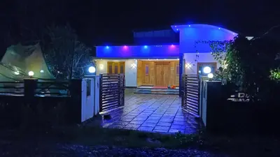 a house lit up at night with blue lights at Service villa in Padinjarathara