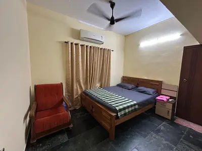 a bedroom with a bed and a red chair at Bluebell Homes A - 3 BHK Near to Calicut in Beypore