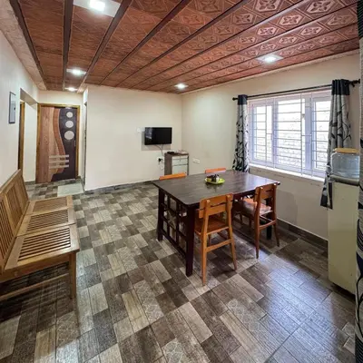 a room with a table and chairs and a television at Ambassador Inn in Kodaikānāl