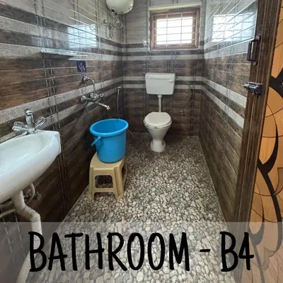 a bathroom with a toilet and a sink and a bucket at Ambassador Inn in Kodaikānāl