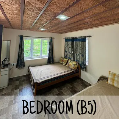 a bedroom with a bed and two windows at Ambassador Inn in Kodaikānāl