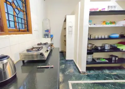 a kitchen with a stove in the middle of a room at Spacious #1BHK Home Stay in Central #Mysore in Mysore