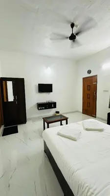 a white room with a bed and a table at Mountain Breeze Neyyans in Attappādi