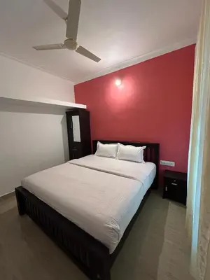 a bedroom with a large bed with a red wall at Le paradiso in Marayoor
