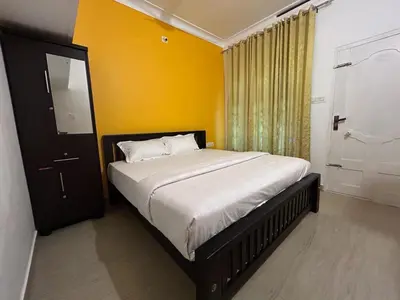 a bedroom with a bed and a yellow wall at Le paradiso in Marayoor
