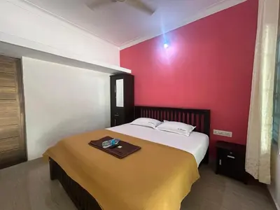 a bedroom with a bed and a red wall at Le paradiso in Marayoor