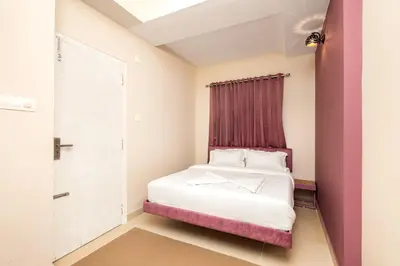 a small bedroom with a bed with a pink headboard at Simqo By Nexa Hotels Group in Kozhikode