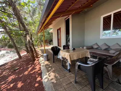 a patio with a table and chairs and a couch at Rocks beach house in Kannur