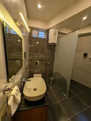 a bathroom with a white sink and a shower at Sihi Homes in Mysore