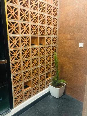 a wooden privacy fence with a plant next to a building at Sihi Homes in Mysore