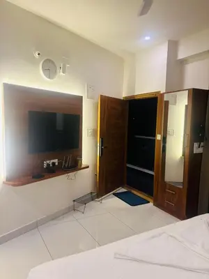 a bedroom with a bed and a flat screen tv at Sihi Homes in Mysore