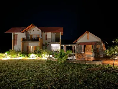a large house at night with a yard at Birdwing - Experiential Farmstay Resort by GoodEarth