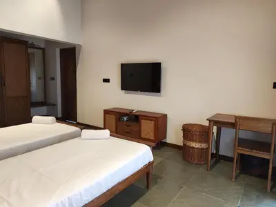 a bedroom with two beds and a flat screen tv at Birdwing - Experiential Farmstay Resort by GoodEarth
