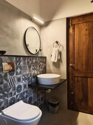 a bathroom with a toilet and a sink and a mirror at Birdwing - Experiential Farmstay Resort by GoodEarth