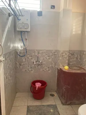 a bathroom with a shower with a red bucket at Abhi home stay in Mysore