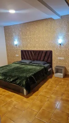 a bedroom with a bed with a green comforter at green mountain homestay in Ooty