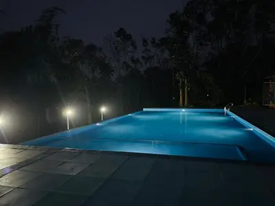 an empty swimming pool at night with lights at Misty Night Wayanad Pool Resort in Wayanad