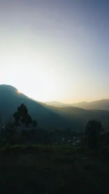 a view of a mountain with the sun setting on the horizon at EKa Forest in Vattavada