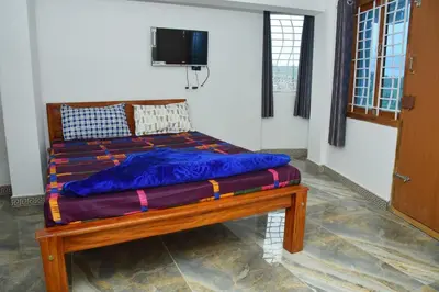 a bed with a blue comforter in a room at Murugan Homestays in Vālpārai