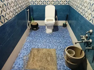 a bathroom with a toilet and a blue tiled floor at Bakka house of joy in Napoklu