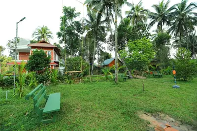 a park with a bench in front of a house at DJ River Meadows Resort in Wayanad
